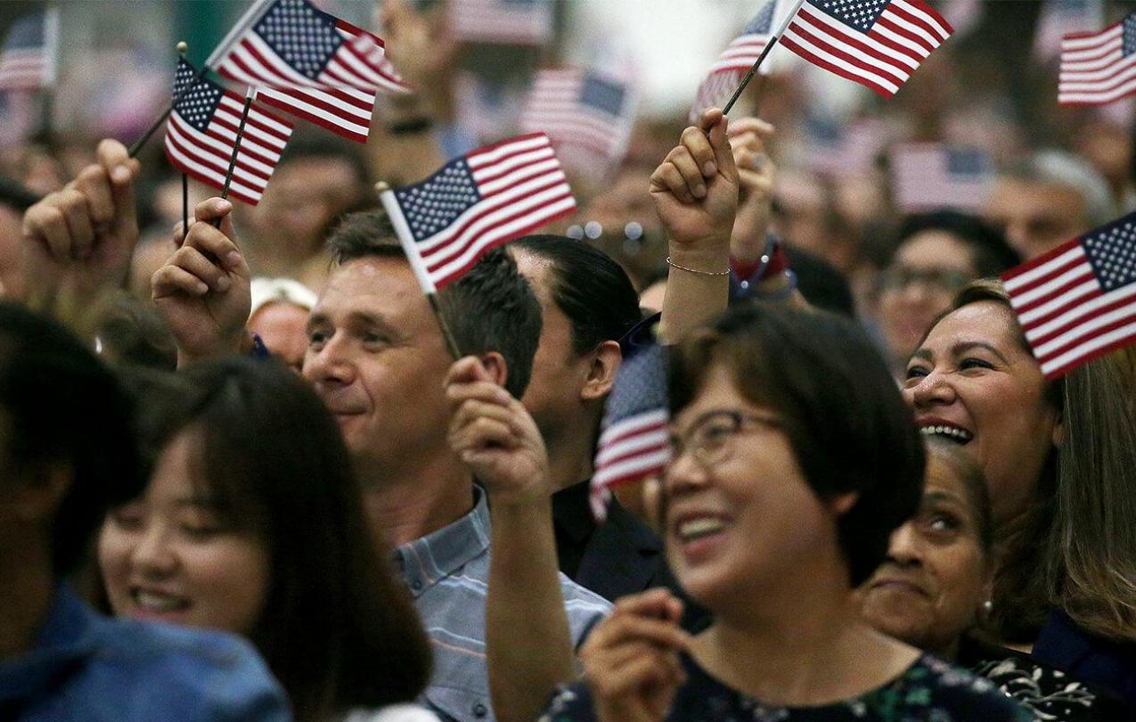 Diverse crowd of people waving small American flags